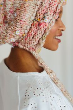 a woman wearing a knitted hat with flowers on it's brimming