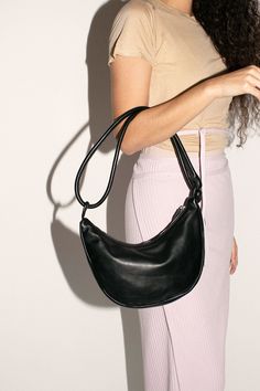 Half moon shaped bag in vegetable tanned semi-aniline cowhide, 100% leather. 11" wide, 7" deep with a 10" strap drop. Doubled, knotted, rolled leather handle and zip closure. Leather Baguette Bag With Round Handle For Everyday, Soft Leather Satchel With Round Handle, On-the-go Hobo Bag With Double Handle, Black Hobo Bag With Double Handle And Branded Hardware, Black Hobo Bag With Detachable Round Handle, Black On-the-go Shoulder Bag With Double Handle, Black Textured Leather Hobo Bag For On-the-go, Bow Bag, Moon Shapes