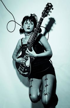 a woman in fishnet stockings holding an electric guitar