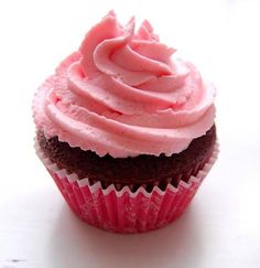 a pink frosted cupcake sitting on top of a white table