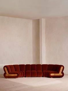 a large sectional couch sitting on top of a white floor next to a tall wall