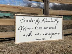 a sign that is on the ground in front of a fence with grass and hay