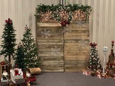 there are many small christmas trees in front of a wooden wall with snowflakes on it