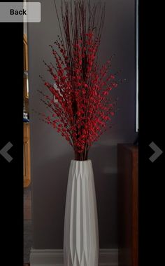 a white vase with red flowers in it