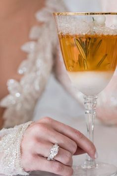 a close up of a person holding a wine glass with a ring on the finger