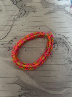 a pink and green bracelet sitting on top of a piece of paper