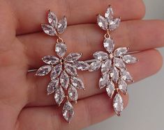 a pair of gold tone earrings with clear crystal stones and leaves hanging from the back