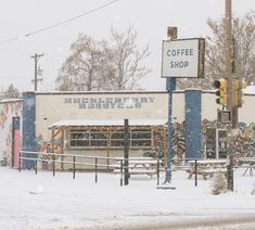 a street sign in front of a coffee shop on a snowy day