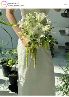 a woman in a white dress holding a bouquet of green and white flowers on her wedding day