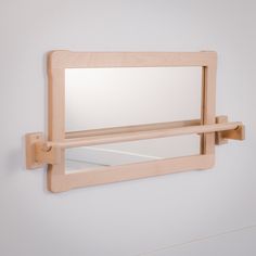 a mirror mounted to the side of a wall with a wooden frame and hooks on it