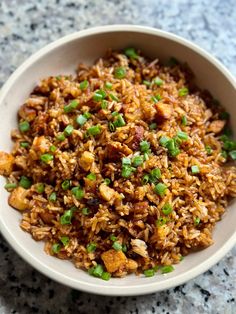 a white bowl filled with rice and green onions