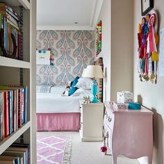 a bedroom with a bed, desk and bookshelf filled with lots of books