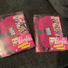 two barbie doll packagings sitting on a couch