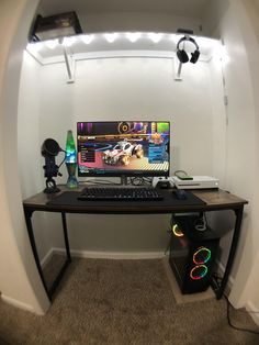 a desk with a computer monitor and keyboard on it in front of a white wall