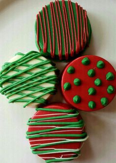 three decorated cookies sitting on top of a white plate with green and red icing