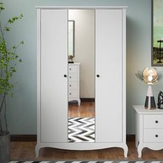 a white wardrobe with mirrored doors and drawers in a room next to a plant on a table