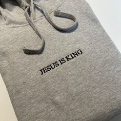 Jesus is King Embroidered T-Shirt, Embroidered Hoodie, Christian Based Clothing, Faith Apparel, Stitched Pullover hooded sweatshirt - Bible Gift Minimalist  - 80% Cotton - 20% Polyester - 7.8 oz/y² Shop: Tiny home shop located in California. All garments are printed to order, handcrafted individually.  I will never use third party cheap labor print shops or mass production drop shippers.  Every Garment is designed, printed, and packaged independently by me. Thank you for supporting someone who i Hooded Tops With Letter Embroidery For Winter, Cotton Long Sleeve Hoodie With Embroidered Text, Cotton Hoodie With Embroidered Text And Long Sleeves, Long Sleeve Cotton Hoodie With Embroidered Text, Casual Hooded Top With Embroidered Text, Winter Hoodie With Letter Embroidery And Relaxed Fit, Embroidered Hoodie With Relaxed Fit For Streetwear, Gray Hoodie Sweatshirt With Embroidered Logo, Gray Embroidered Logo Hoodie Sweatshirt