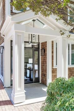 the front entrance to a home with white pillars and brickwork on it's sides