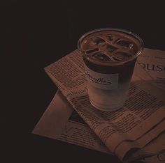 a cup of coffee sitting on top of a newspaper next to a glass of liquid