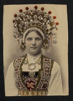 an old photo of a woman wearing a headdress with beads and jewels on it