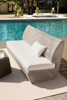 a white couch sitting on top of a wooden floor next to a swimming pool