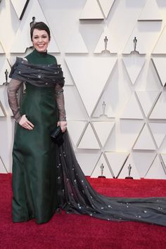 woman in green dress on red carpet at oscars with black and grey shawl