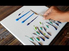 a person is using scissors to cut out paint on a piece of paper with blue, green and white colors