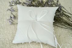 a white pillow with a bow on it and some lavenders in the back ground