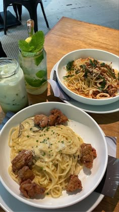 two plates of spaghetti with meat and sauce on the table next to a glass of milk