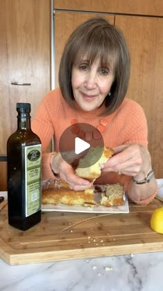 a woman sitting at a table with food in front of her and an olive oil bottle