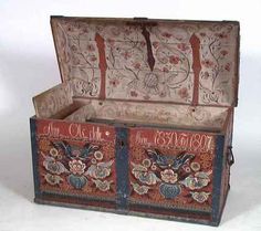 an old wooden box with floral designs on the front and sides, sitting on a white surface