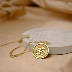 This exquisite Gold Om necklace pendant is a spiritual and stylish accessory that will elevate any outfit. Crafted with precision and care, this stunning pendant features a delicate Om symbol in shimmering gold. The Om symbol is a sacred sound and spiritual icon in Hinduism, Buddhism, and other religions, representing the oneness of all creation. Wear this beautiful necklace pendant as a daily reminder of peace, harmony, and unity. It also makes a thoughtful gift for friends and loved ones seeking enlightenment and inner peace. Add this Gold Om necklace pendant to your jewelry collection and shine with divine grace. ✨ Captivate with Gold Om Necklace ✨ Made to Match Your Style: Timeless Silver: Crafted from genuine 925 sterling silver for enduring beauty. Luxurious Gold: Choose your perfect Spiritual Gold Jewelry For Meditation, Spiritual Gold Plated Medallion Charm Necklaces, Gold Plated Spiritual Medallion Charm Necklaces, Spiritual Gold Plated Medallion Charm Necklace, Spiritual Gold-plated Medallion Pendant Necklace, Symbolic Round Pendant Jewelry For Meditation, Spiritual Yellow Gold Medallion Necklace With Large Pendant, Gold Charm Necklace With Coin Pendant Symbolic Style, Symbolic Gold Charm Necklace With Coin Pendant