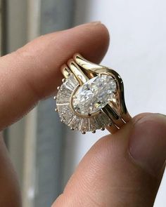 a close up of a person's hand holding a ring with diamonds on it