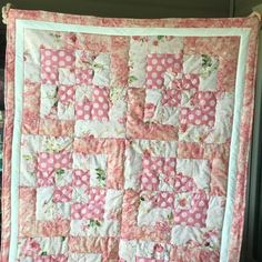 a pink and white quilt hanging on the wall