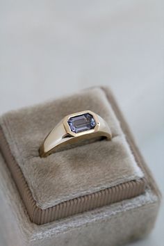 This yellow gold signet ring features a bezel set Emerald Cut Lilac Spinel, in east-west orientation. Perfectly showcasing the beautiful Spinel, this one of a kind ring could be worn as an alternative engagement ring, or simply as a cherished everyday ring. Set in 9ct yellow gold, the Emerald Cut Spinel is 0.94ct. The stone is approximately 7.1mm x 4.9mm. This ring is currently an Australian size L, and can be resized up or down. This ring is one of a kind. Once sold, it will be gone forever. Ho Bezel Set Gemstone Engagement Ring, Simple Non Traditional Wedding Rings, Signet Engagement Rings, East West Engagement Ring, Ruby Ring Designs, Engagement Ring For Men, David Ring, Couple Ring Design, Engagement Rings Couple