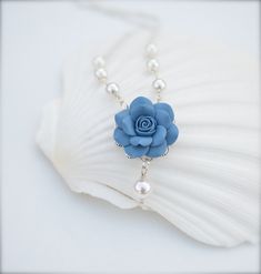 "Featuring 25-26mmmm Hand Sculpted Dusty Blue Rose Centered Necklace. Matching Jewelry availabe in my shop. Drop a note if you prfer different shade blue. Material and size : Rose Clay Flower is approximately 25-26mm across. 6-8mm white glass pearls as pictured. Cream pearls available. Swarovski available with additional cost. Silver plated chain (pictured). Antiqued brass and gold palted chain available . The entire length approximately 16.1/2 inches with 2 \" extender , if you need to resize t Elegant Blue Flower Necklace, Blue Wedding Jewelry With Flower Charm, Blue Flower Necklace For Wedding, Necklace Matching, Clay Flower, Pearl Cream, Blue Bridesmaids, Matching Jewelry, Bridesmaid Necklace