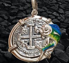 This is a beautiful setting. The bezel is solid sterling silver and the mahi mahi is handpainted with enamel. There is also a white topaz set in its eye. The coin is made from the silver bars recovered from the Atocha and comes with a certificate stating that. This piece is stunning in person. Silver Symbolic Jewelry Souvenir, Engraved Round Pendant Jewelry As Souvenir, Engraved Round Pendant Jewelry For Souvenir, Unique Silver Coin-shaped Jewelry, Unique Silver Coin Jewelry, Sterling Silver Coin Jewelry With Polished Finish, Handmade Silver Jewelry As Souvenir, Handmade Silver Jewelry For Souvenir, Handmade Silver Jewelry Souvenir