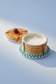 two donuts are sitting on plates next to each other, one has a candle in it