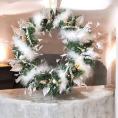 a wreath with white feathers and pine cones