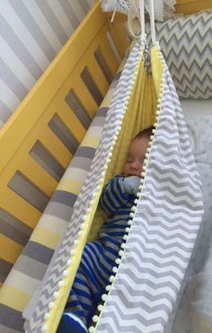 a baby sleeping in a crib next to a yellow and gray blanket on top of a bed