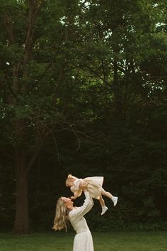 a woman holding a baby up in the air