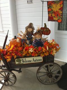 a wagon filled with pumpkins and scarecrows sitting on top of a porch