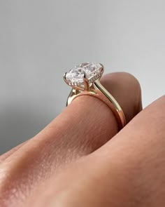 a woman's hand with a diamond ring on top of her finger, showing the center stone