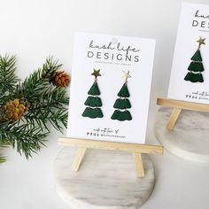 two christmas tree earrings on display next to pine cones