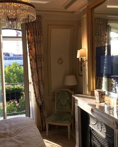 a bedroom with a fireplace, mirror and chandelier on the wall next to it