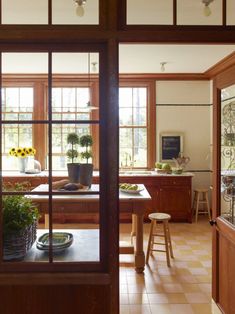 a kitchen with wooden cabinets and tiled flooring next to a window filled with potted plants