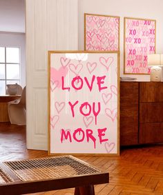 there is a sign that says love you more on the wall next to a table