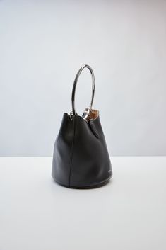 Alaïa's Spring/Summer 2024 collection, features this calf leather top-handle bucket bag. It has a removable tethered zip pouch, magnetic closure, metal rings, metal top handle, and leather lining. Rings Metal, Spring Summer 2024, Zip Pouch, 2024 Collection, Summer 2024, Leather Top, Metal Rings, Magnetic Closure, Top Handle