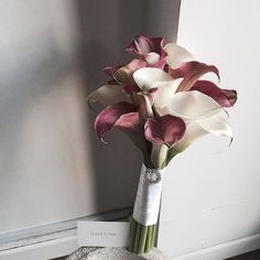 a bouquet of pink and white calla lilies in a vase on the floor