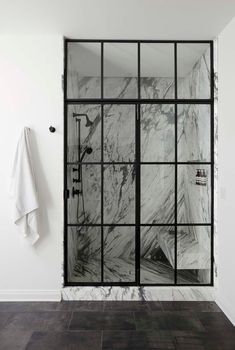 a bathroom with black and white marble tile on the walls, shower head, and towel rack